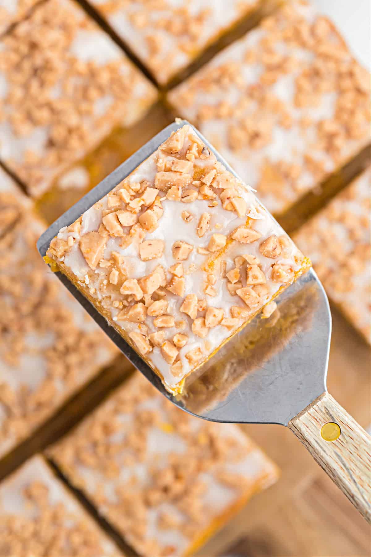 Pumpkin blondies being lifted with a spatula out of baking dish.