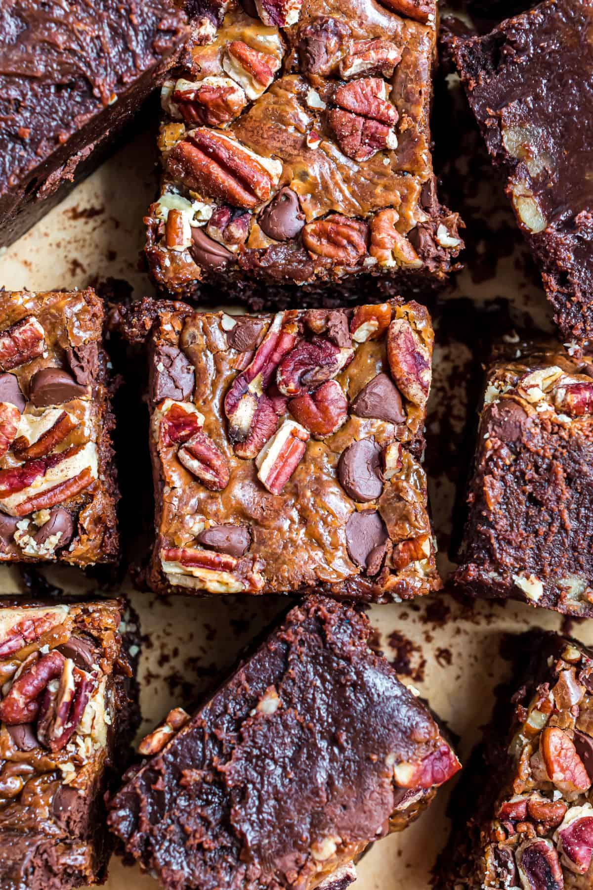Turtle brownies cut into squares on parchment paper.