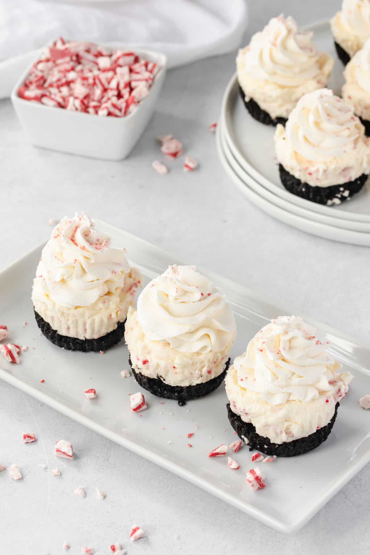 No bake peppermint cheesecakes on a serving platter with sprinkles of andes peppermint crunch candy.