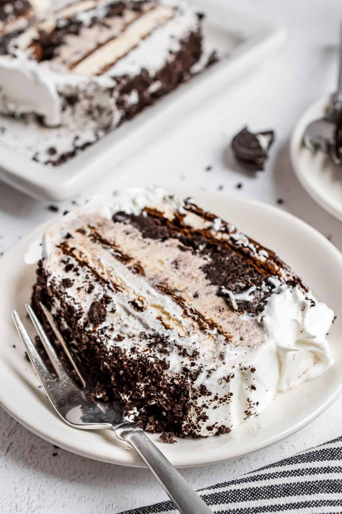 Slice or Oreo ice cream cake on a white plate with fork.