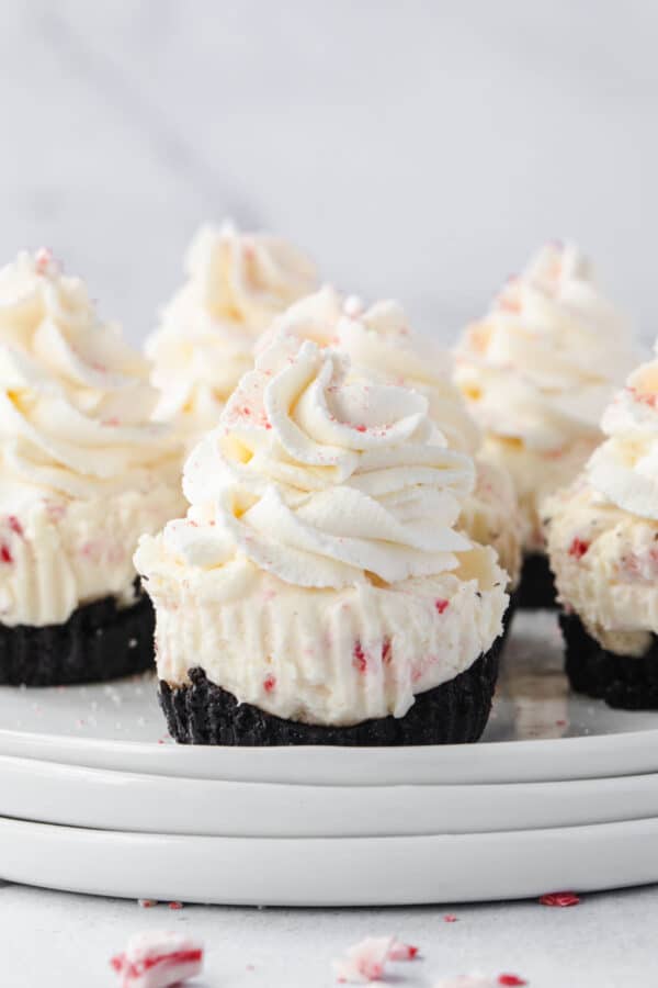 Peppermint cheesecakes on stack of white plates.