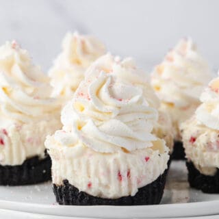 Add merriment to your holiday table with these Peppermint Cheesecakes! Mini no bake cheesecakes are filled with crunchy bits of peppermint candy and topped with whipped cream in this festive and easy dessert.