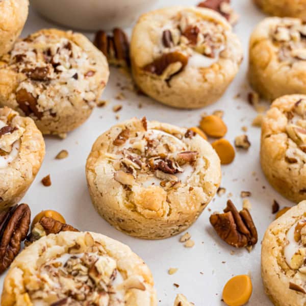 Butterscotch cookie cups topped with chopped pecans, scattered with butterscotch chips and pecan halves for a sweet, nutty treat.
