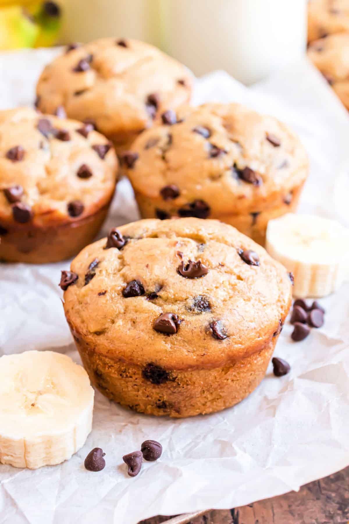 Chocolate chip banana muffins on a piece of parchment paper.