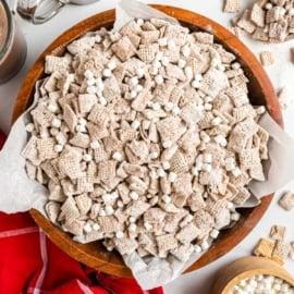 A wooden bowl filled with hot cocoa muddy buddies cereal, coated in powdered sugar and mini marshmallows.