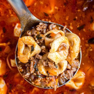 Sausage tortellini soup on a ladle.