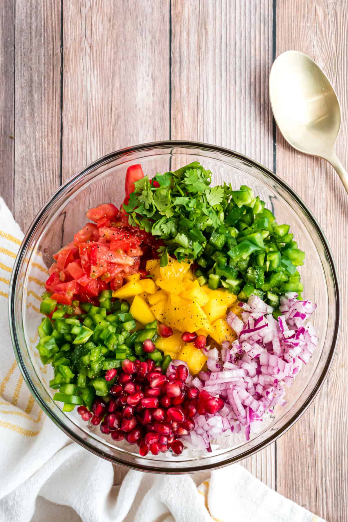 Clear glass bowl with ingredients for mango salsa.