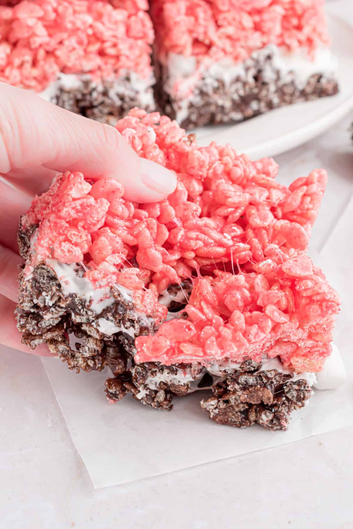 Hand showing gooey neapolitan krispie treats.