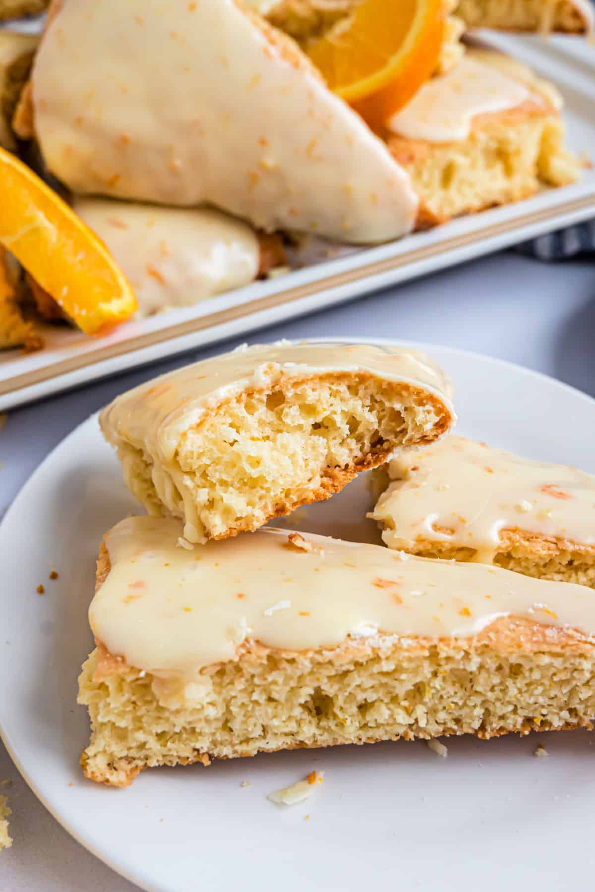 Orange scone on a plate with a bite taken out.