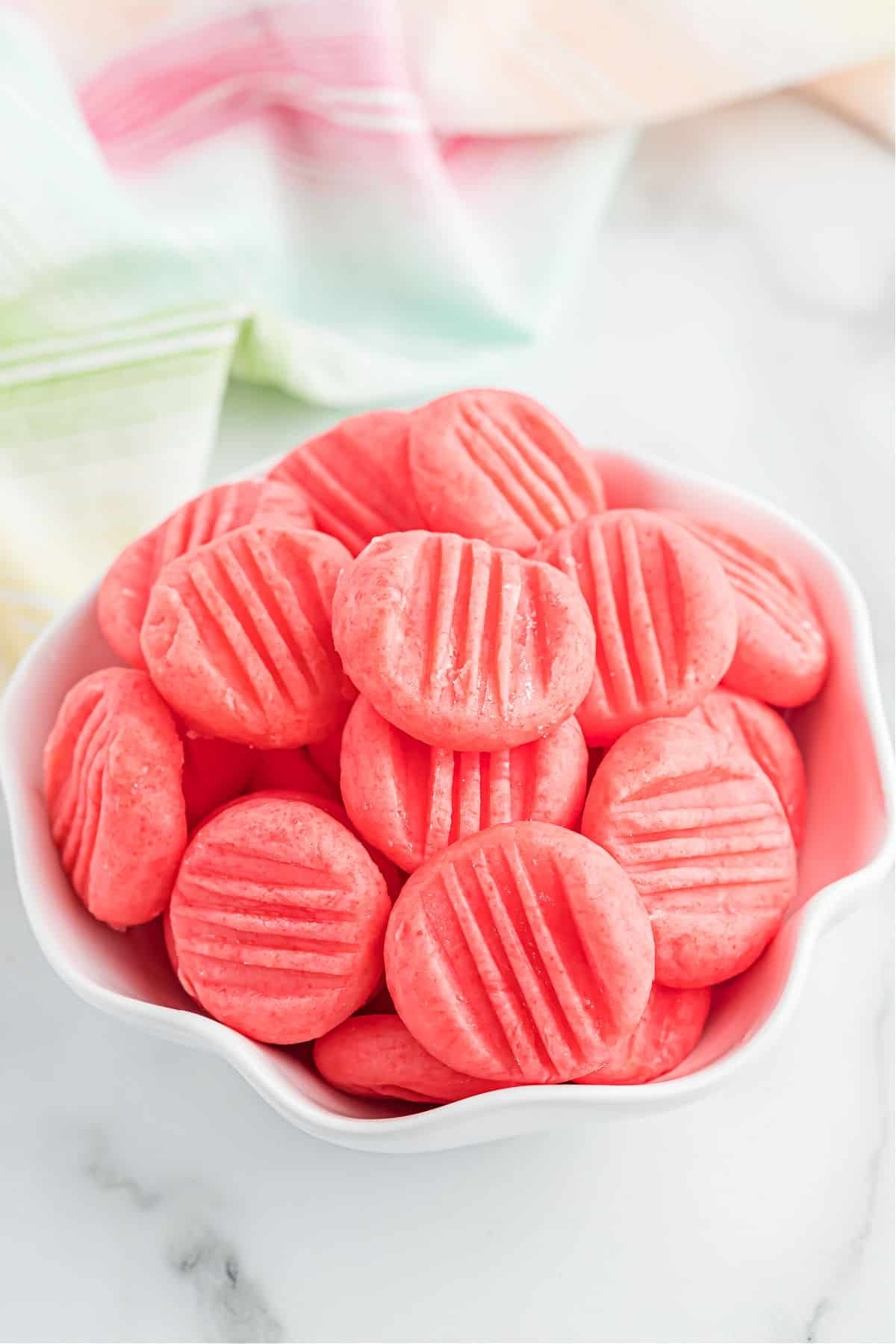 Strawberry mints with fork marks in a white bowl.
