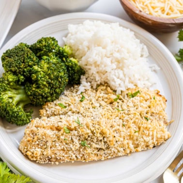 A plate with parmesan crusted tilapia, steamed broccoli, and white rice.