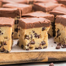 Squares of cookie dough on parchment paper lined cutting board.