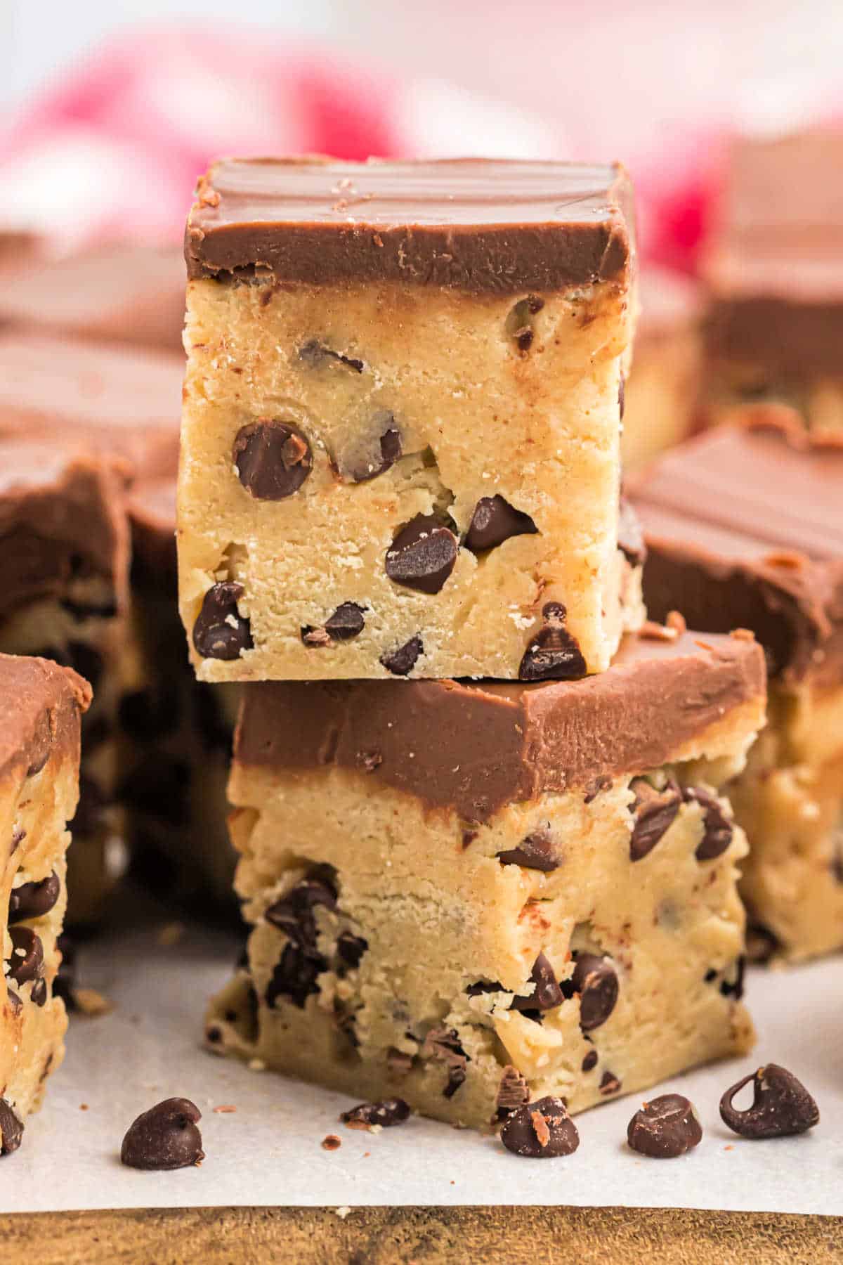 Two squares of cookie dough with chocolate stacked on a piece of parchment paper.