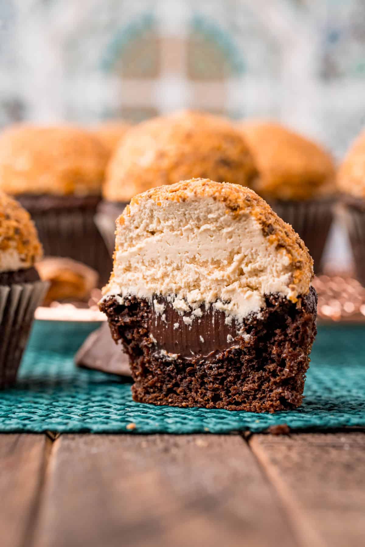 Chocolate cupcake sliced in half revealing fudge filling, peanut butter frosting, and butterfinger candy topping.