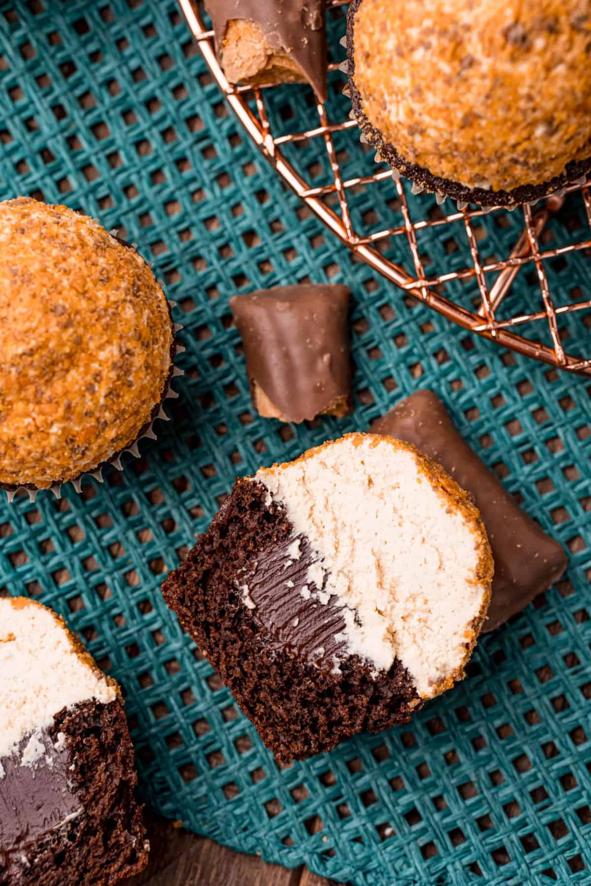 Chocolate cupcake with chocolate ganache, frosting, and butterfinger candy sliced in half.