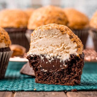 Chocolate cupcake sliced in half revealing ganache, peanut butter frosting, and butterfinger pieces on top.