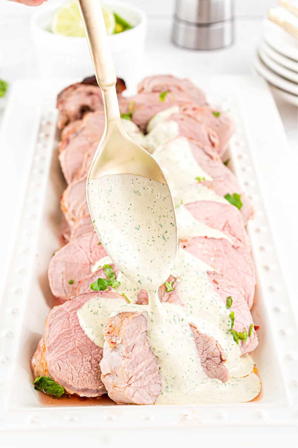 Cilantro lime sauced being spooned over slices of pork tenderloin.