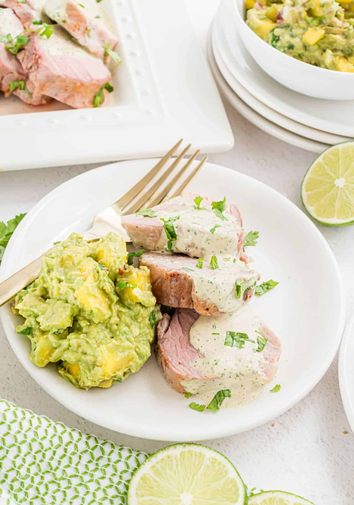 Pork tenderloin with mango guacamole on a white dinner plate.