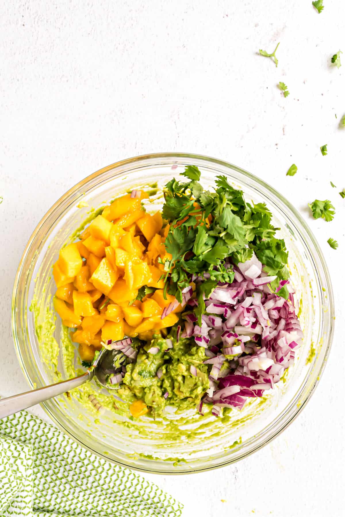 Ingredients for mango guacamole in a clear glass bowl.
