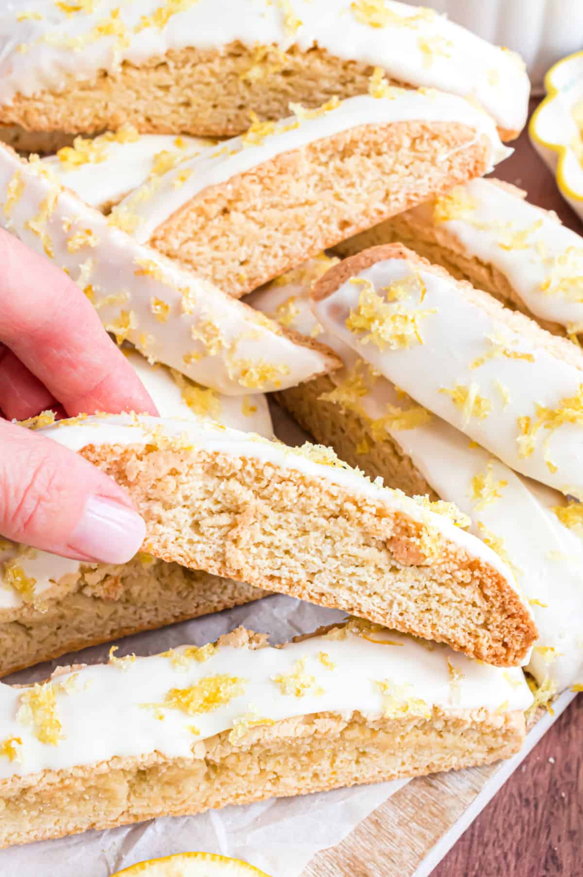 Lemon biscotti being picked up to dunk in coffee.