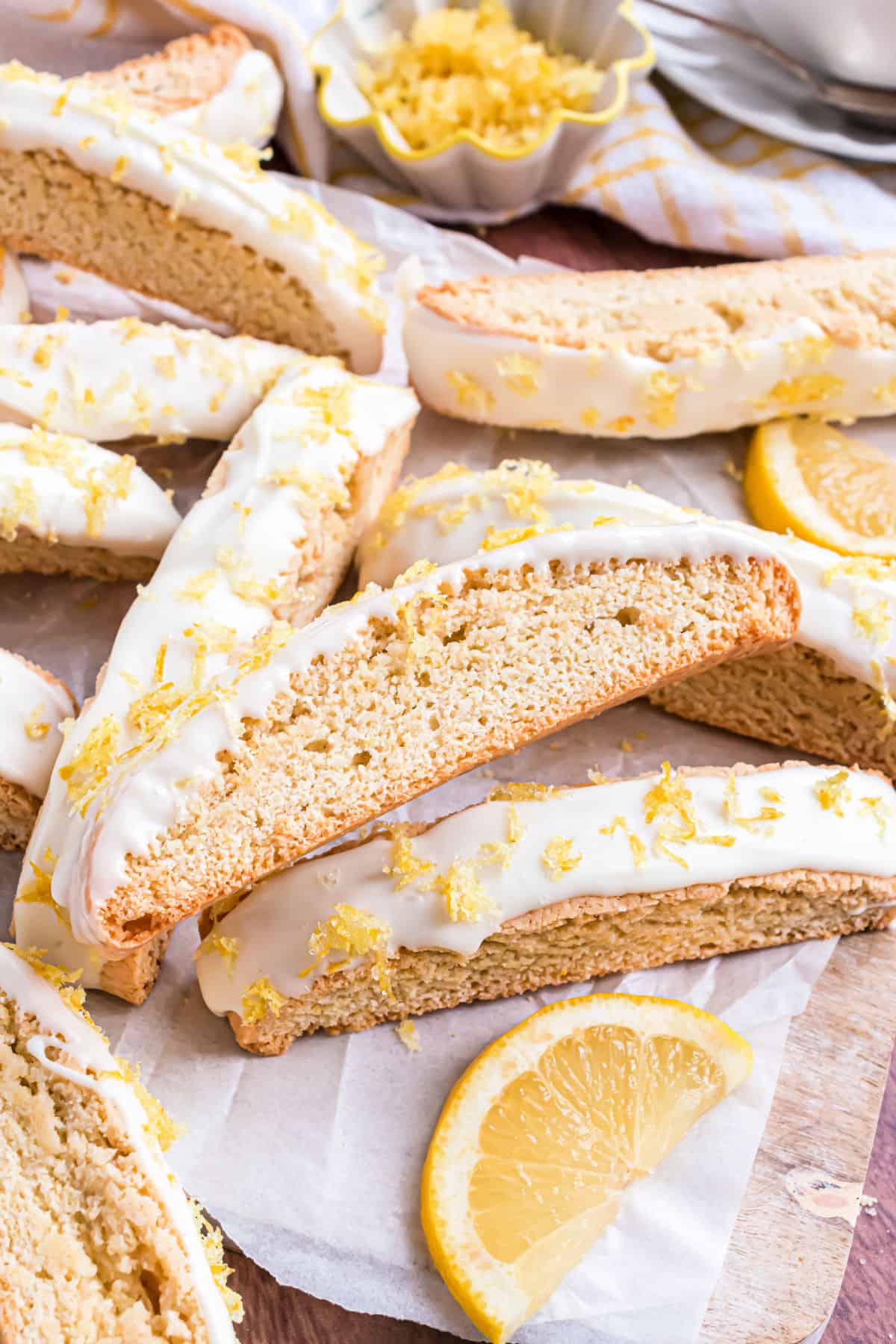 Lemon biscotti dipped in white chocolate and stacked on parchment paper.