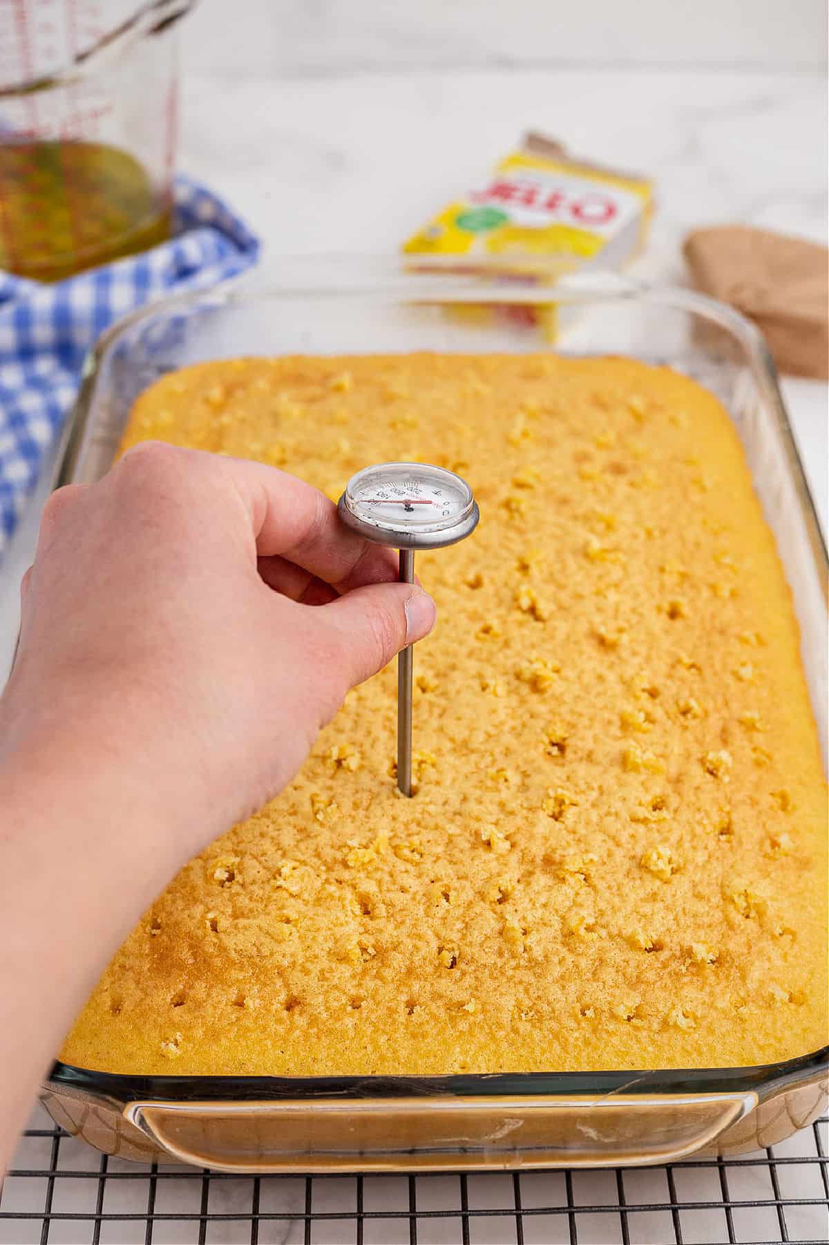 Holes being poked into a cake using a meat thermometer.