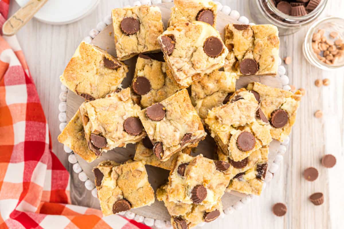 Peanut butter cheesecake bars stacked on a white plate.