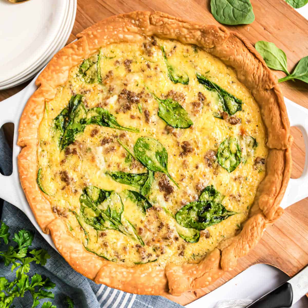 Spinach quiche uncut on a serving board.