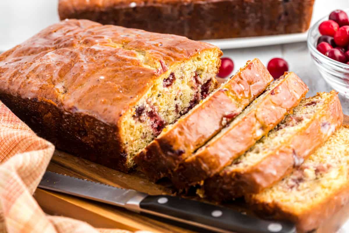 Loaf of cranberry bread sliced on cutting board.