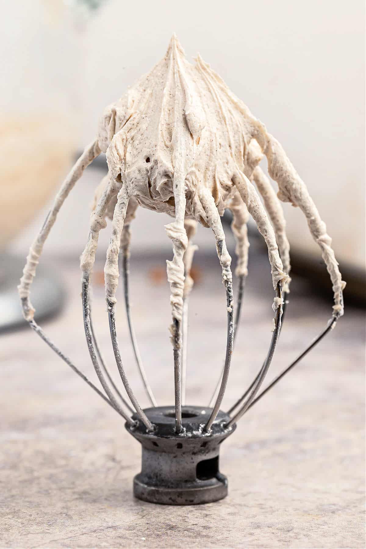 Cinnamon frosting on a whisk for oatmeal cookie bars.