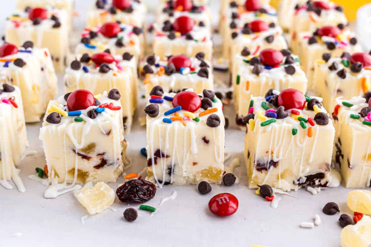 Banana Split Fudge: White fudge squares topped with chocolate chips, sprinkles, cherries, and drizzled white chocolate.