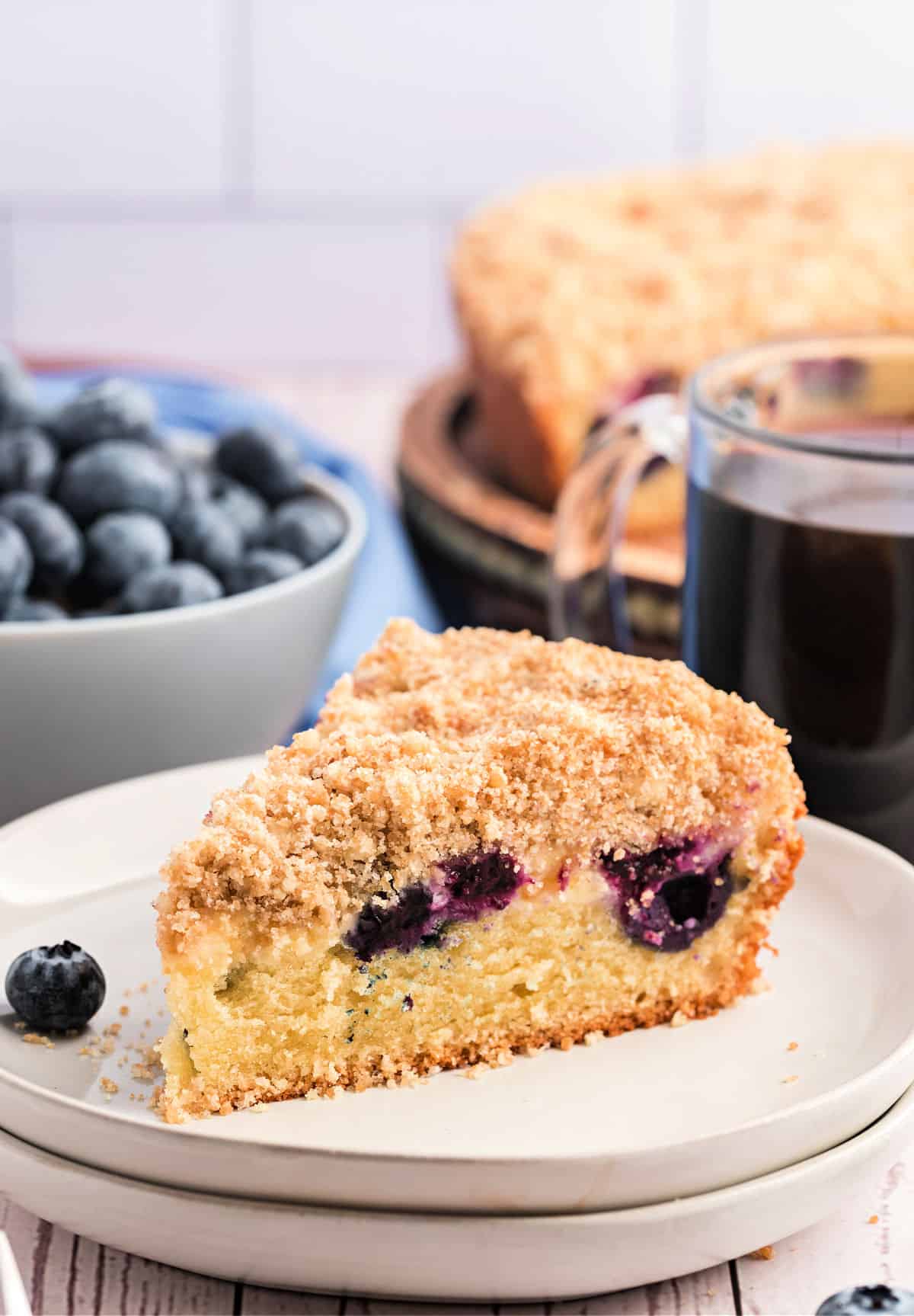 Slice of blueberry coffee cake on white plate.
