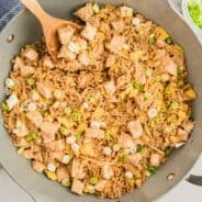 Chicken fried rice in a skillet with a wooden spoon.