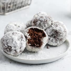 Chocolate donut holes on a white plate.
