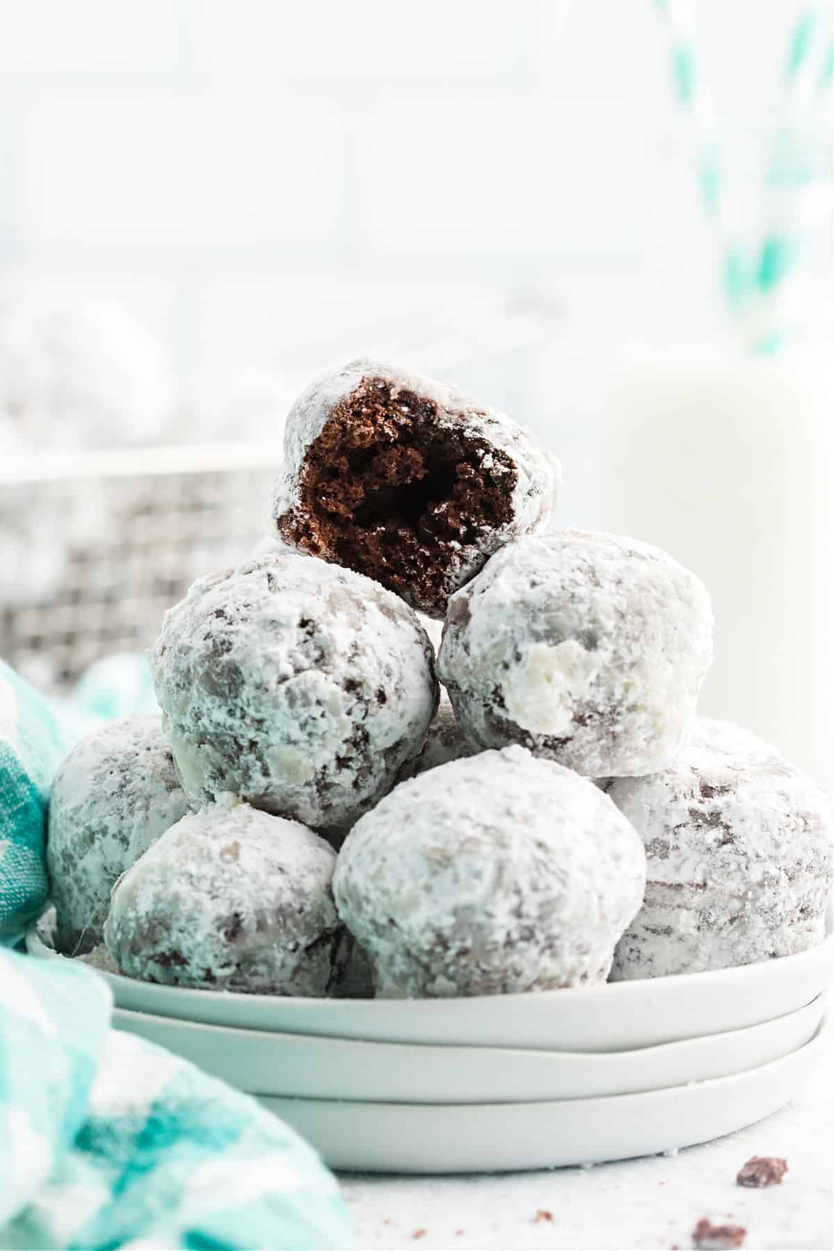 Stack of chocolate donuts rolled in powdered sugar.