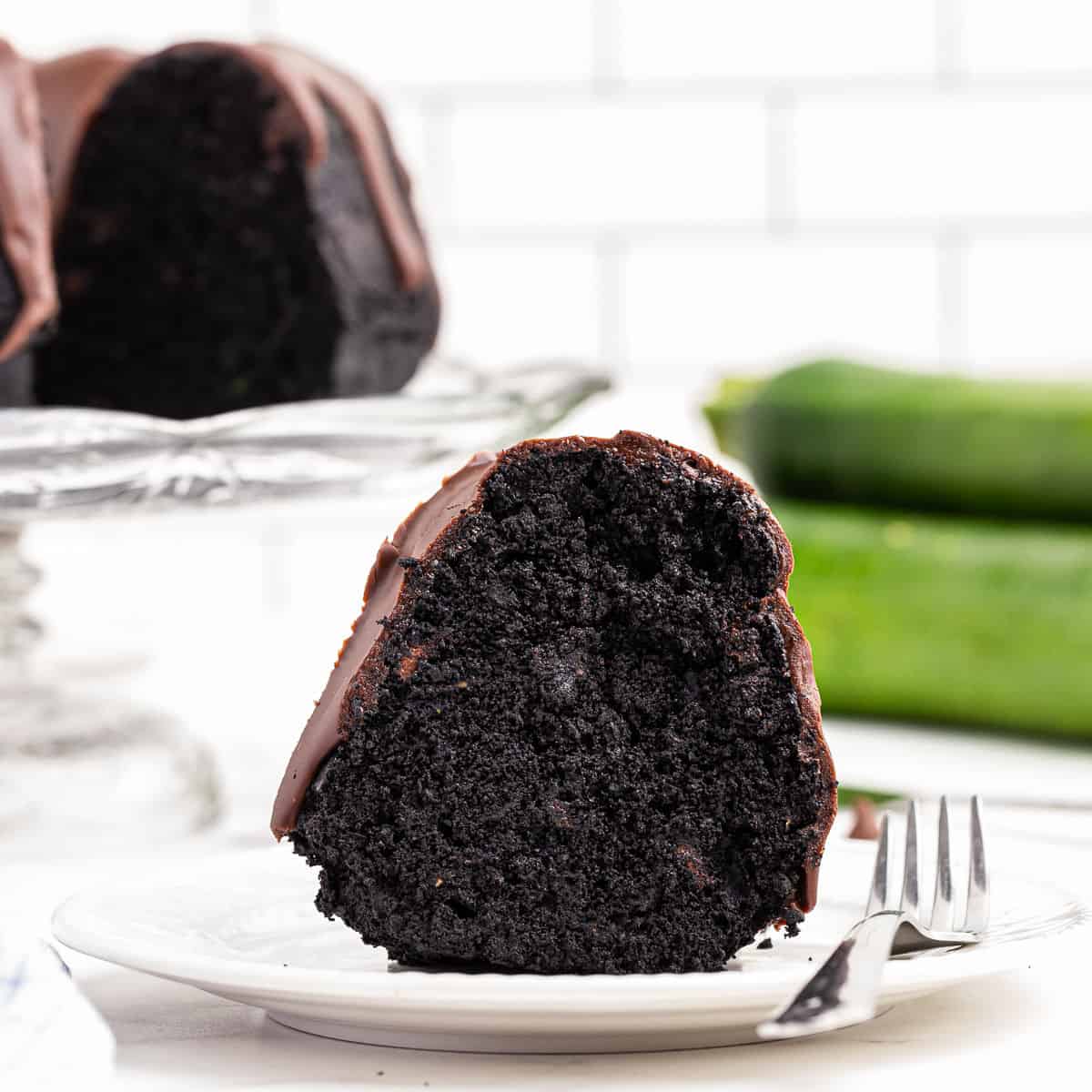 Slice of chocolate zucchini cake on a white plate.