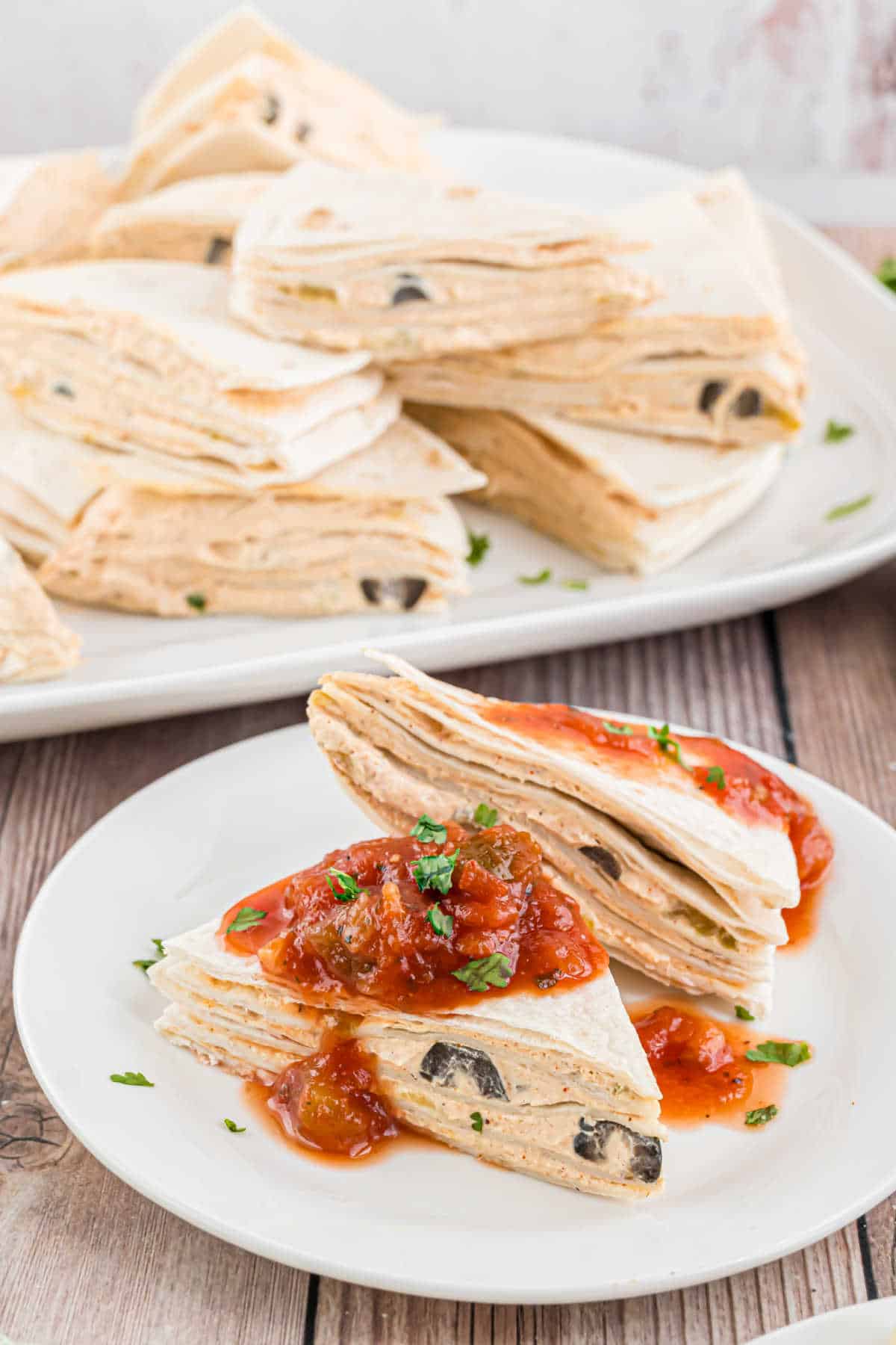 Two taco tortilla triangles with salsa on a white plate.