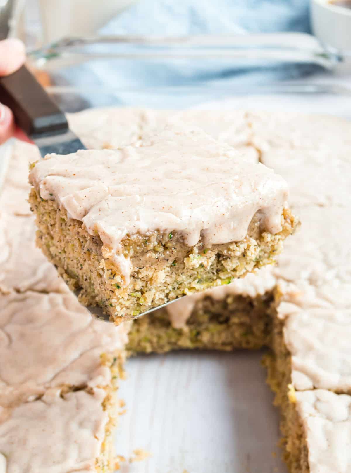 Zucchini banana bars lifted out of a dish with spatula.