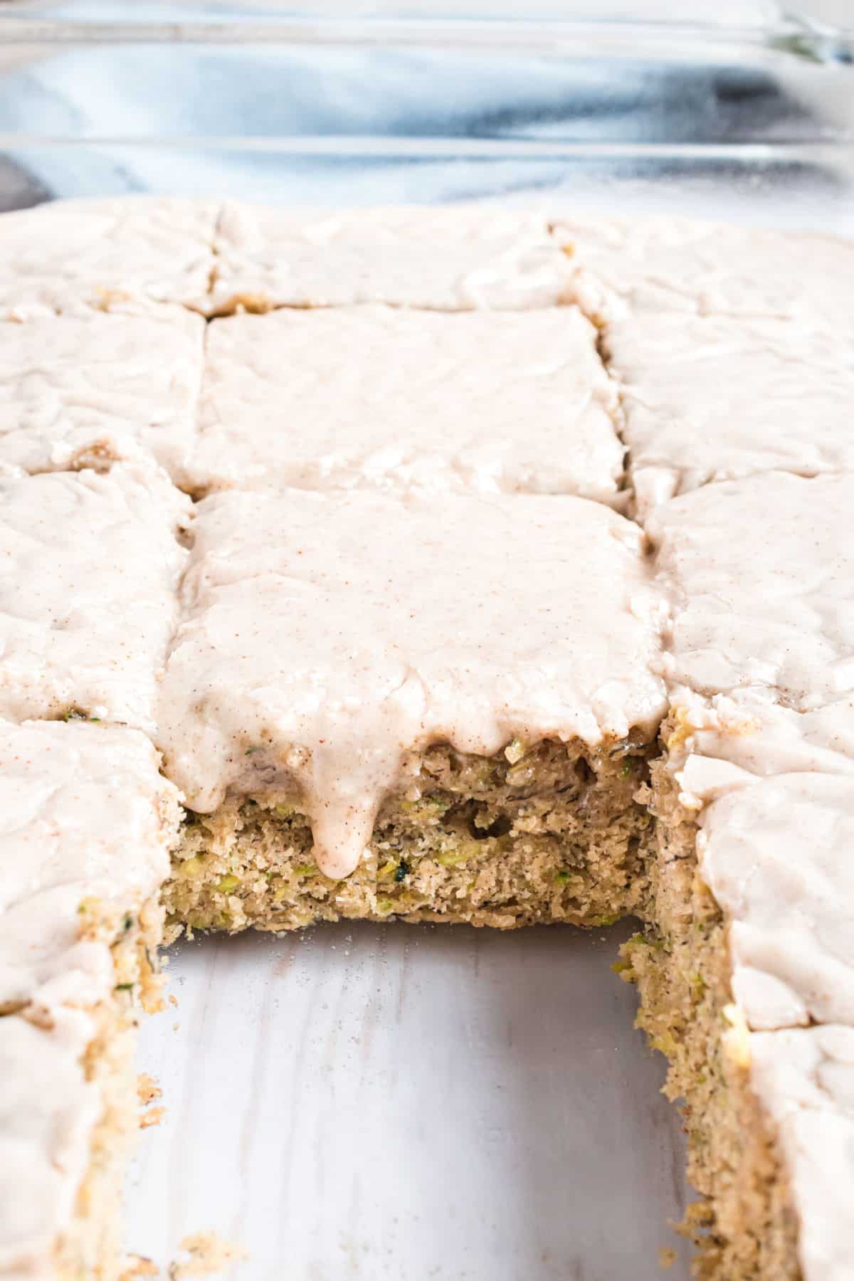 Zucchini banana bars with icing in a 13x9 baking dish.