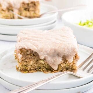 Slice of cinnamon frosted zucchini banana bar on a white plate.