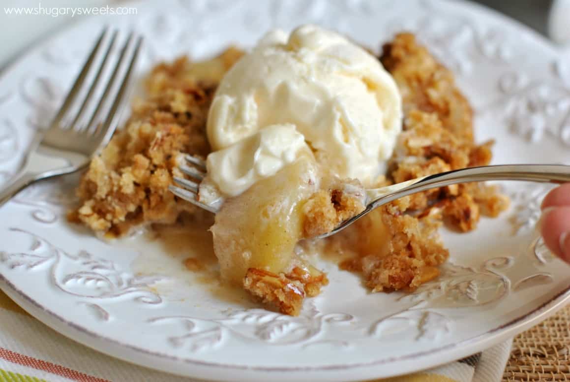 Peach Crisp topped with vanilla ice cream, scooped up with a fork. 