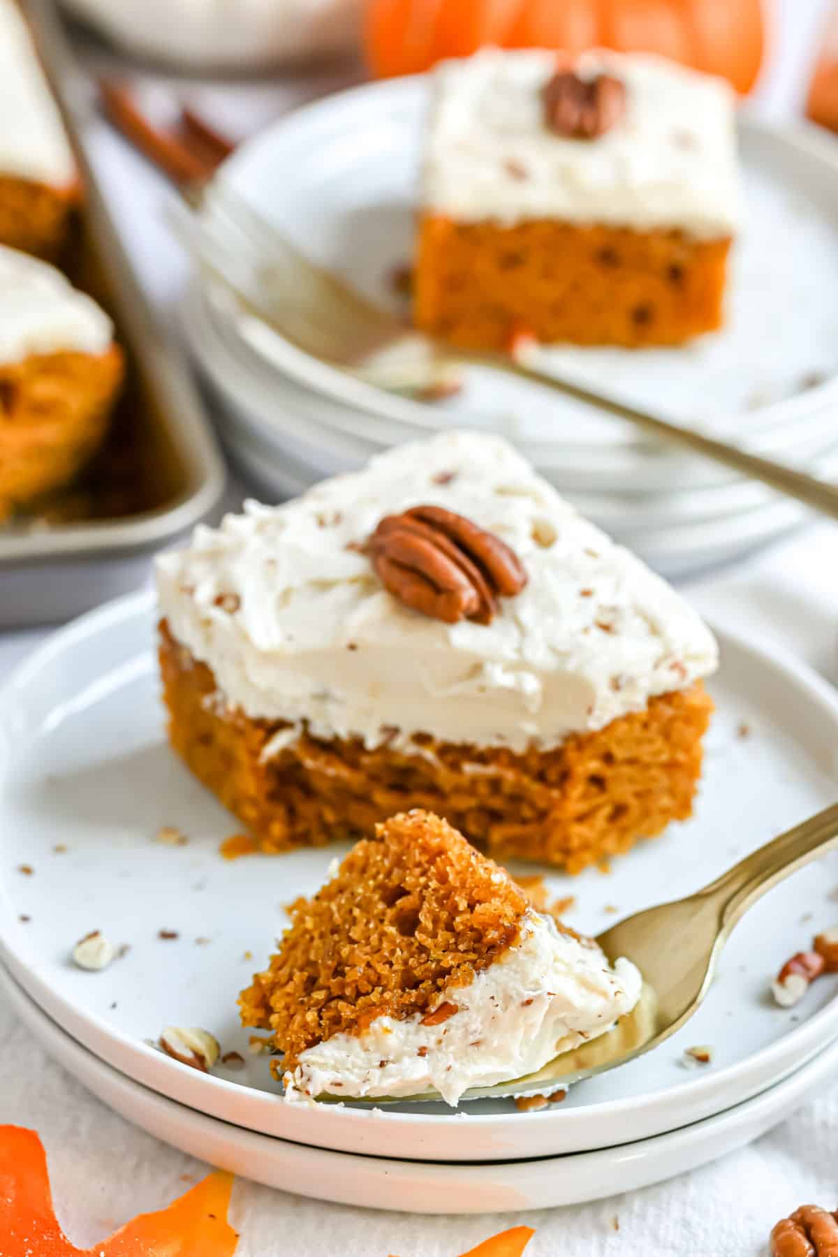 Pumpkin bar with cream cheese frosting on a plate with a bite taken out.