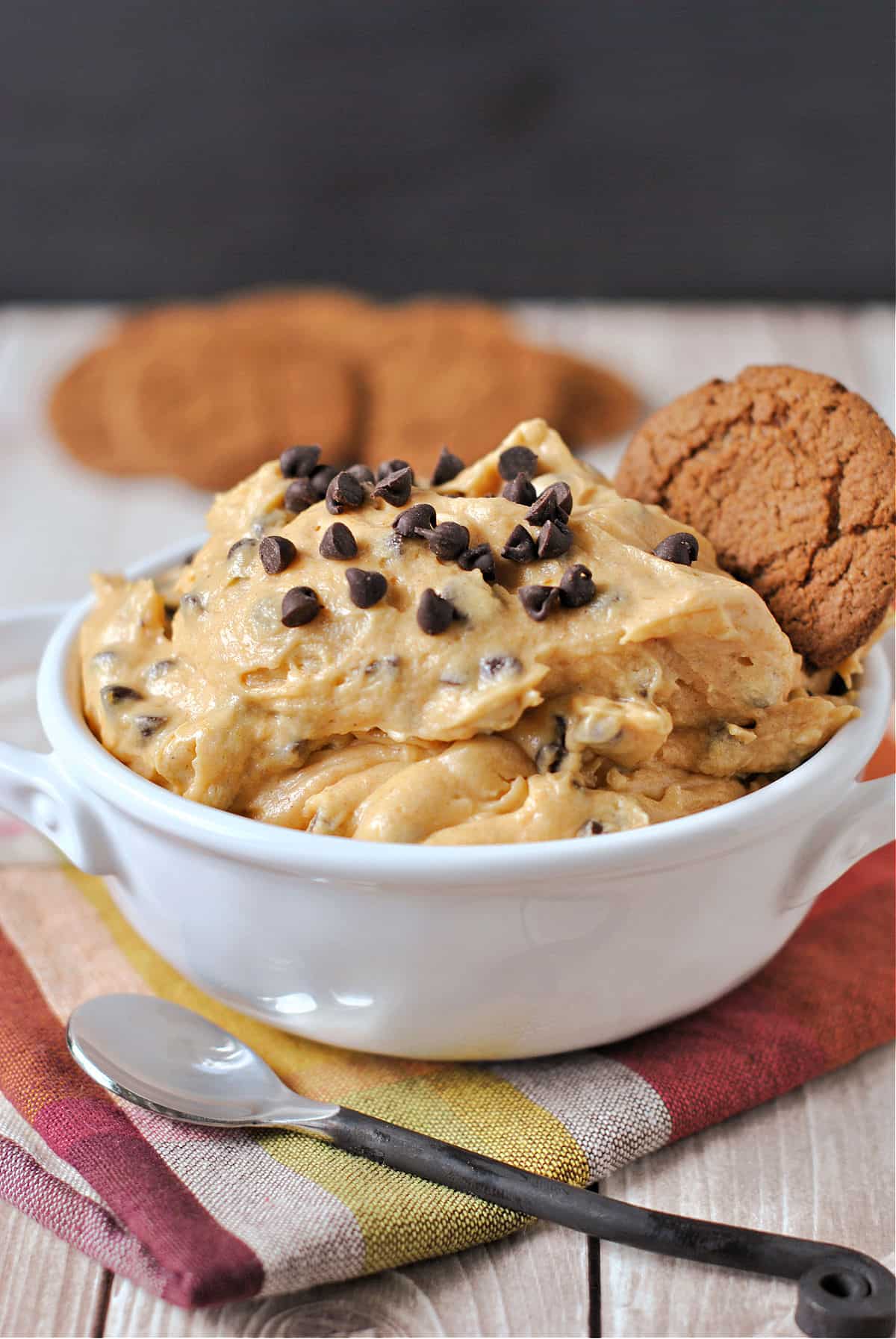 Pumpkin dip with chocolate chips on a top and served with gingersnap cookies.