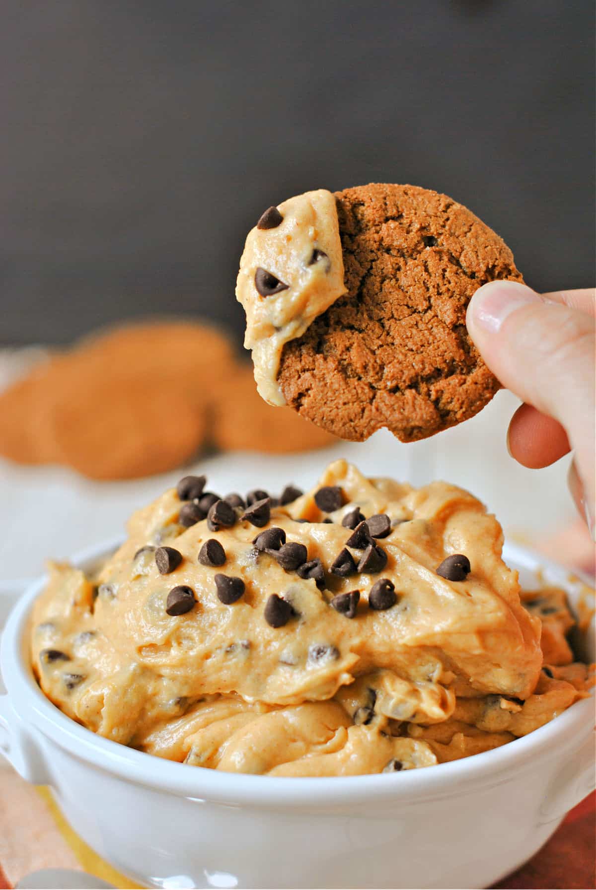 Pumpkin cookie dough dip scooped onto a gingersnap cookie.