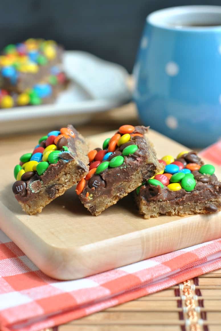 Rainbow fudgy chocolate chip bars on a wooden cutting board.