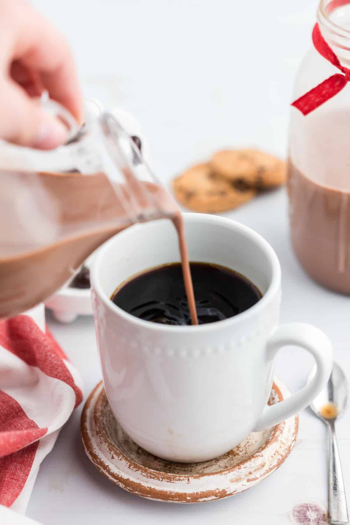 Chocolate chip coffee creamer being poured into hot black coffee.