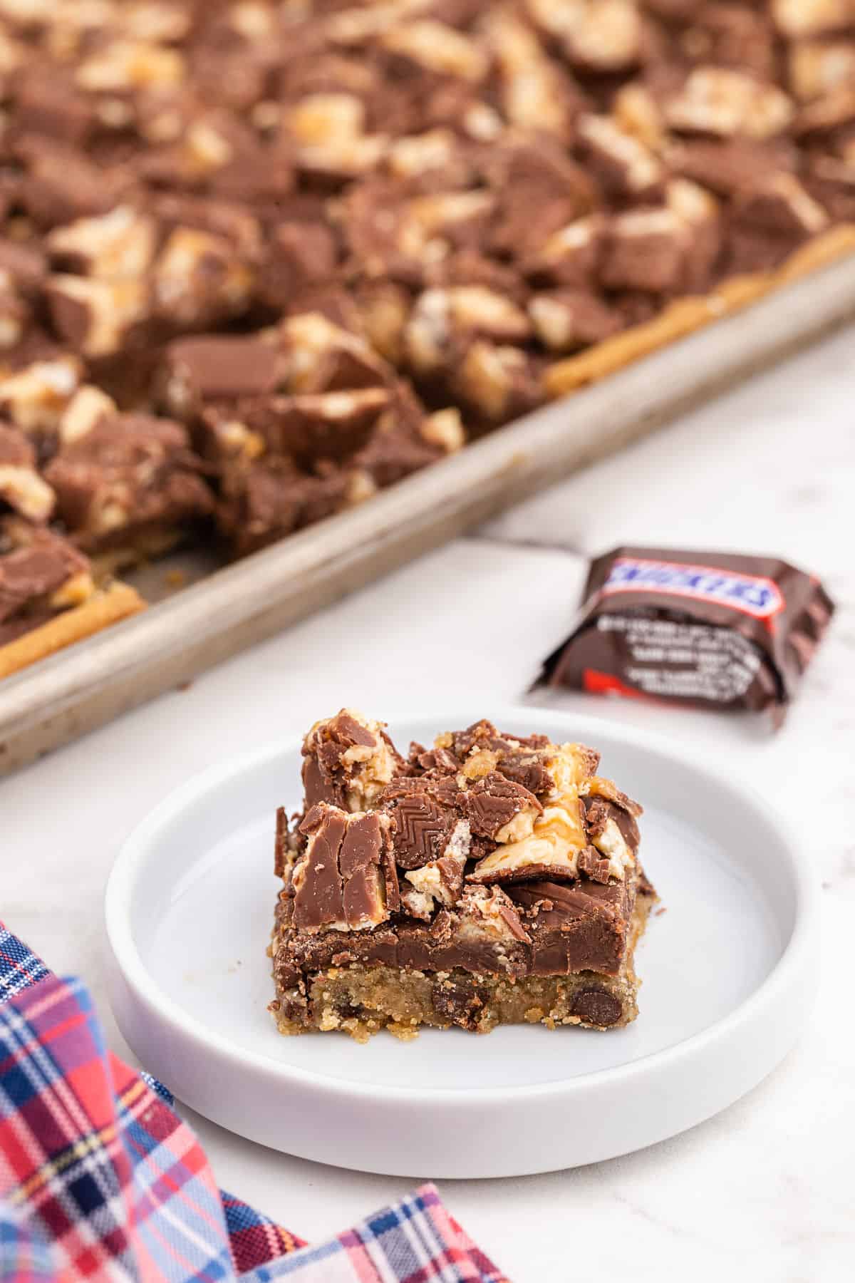 Slice of chocolate chip snicker's cookie bar on a white plate.