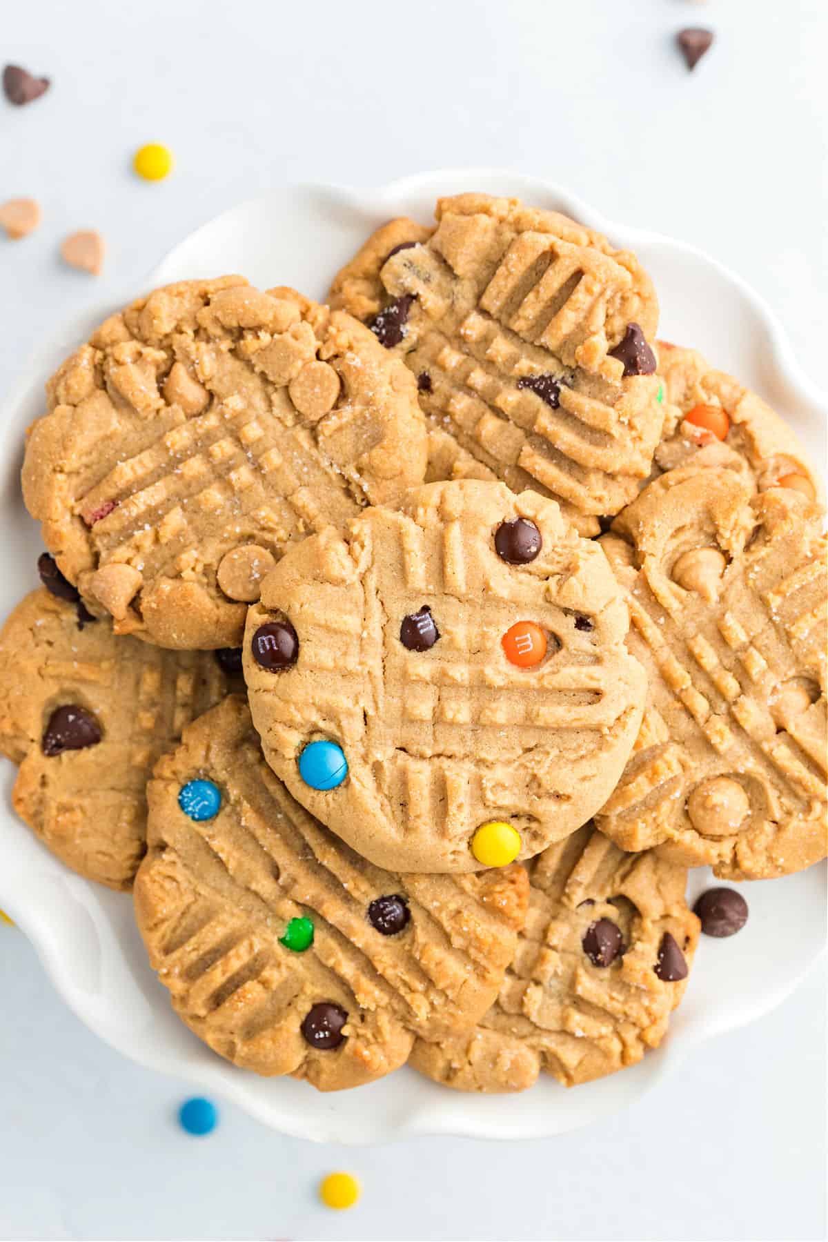 White plate with stack of peanut butter cookies, some topped with m&m's.