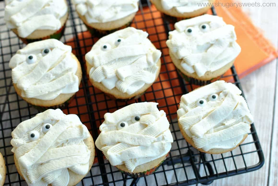 Black wire rack with vanilla bean frosted cupcakes for halloween.