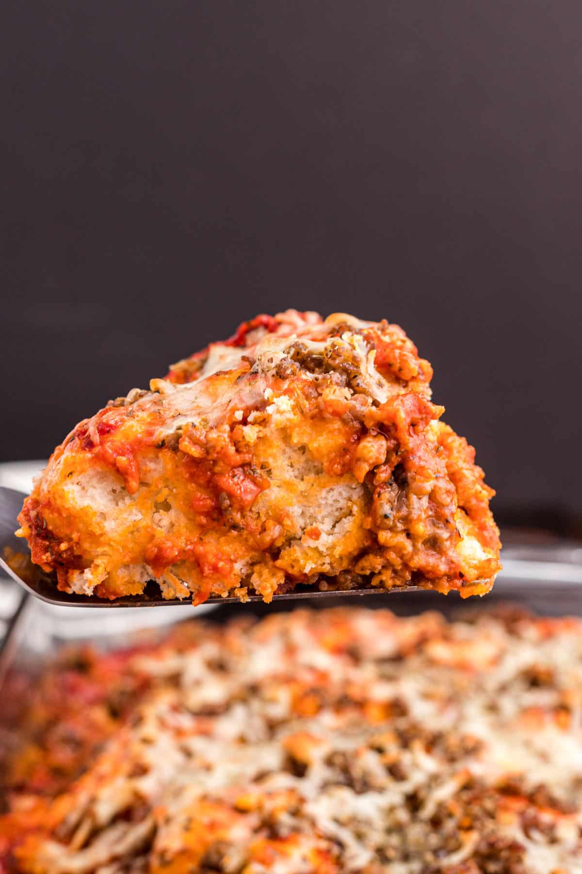 Pizza casserole being served with spatula out of baking dish.